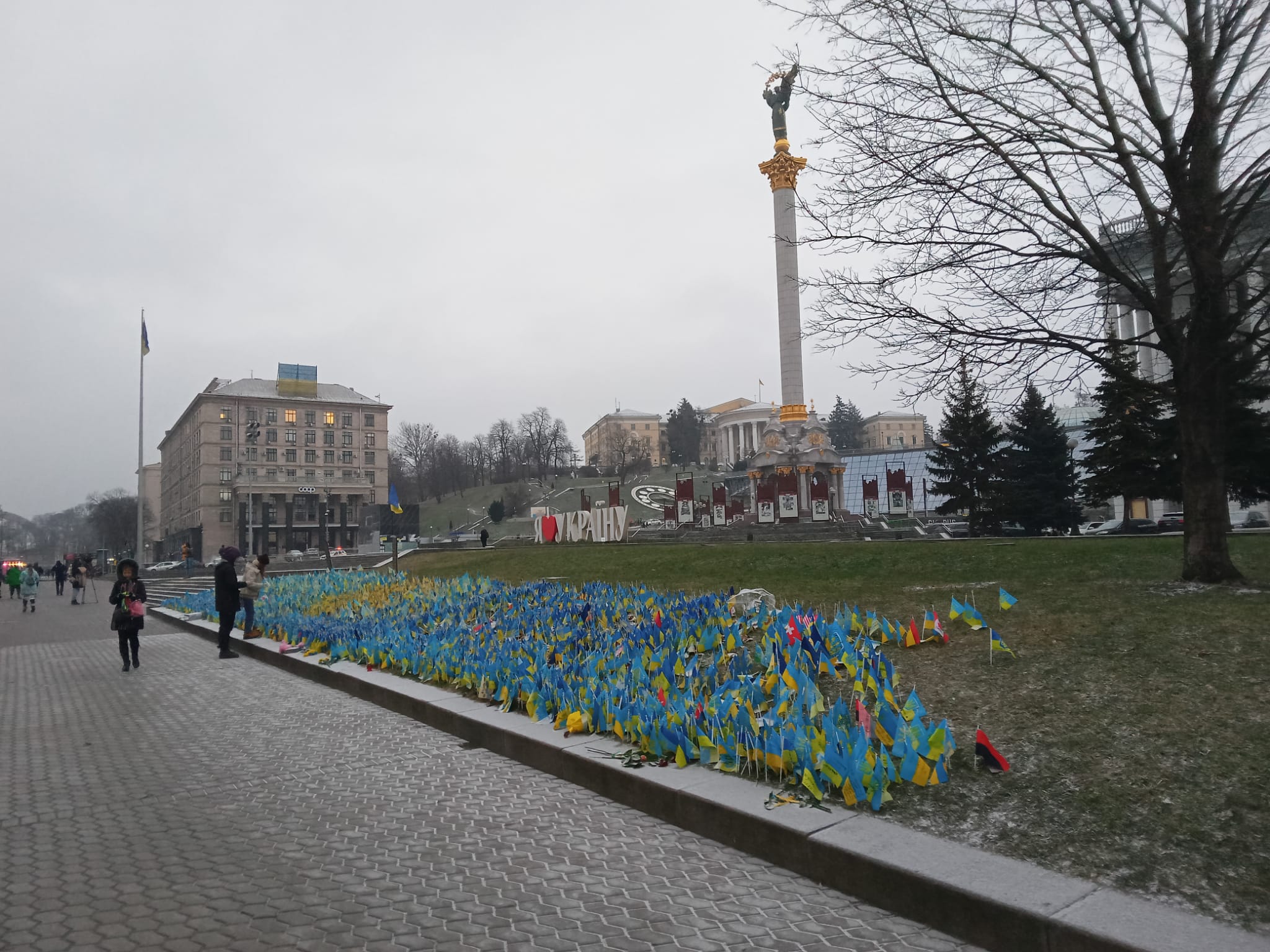 En la Plaza de la Independencia de Kiev, una mujer madura de nombre Katya, nos aborda ofreciéndonos pulseras con la bandera patria. Quiere un donativo para la causa. Junto a ella centenares de banderas clavadas con los nombres de los mártires y las fechas en que fueron muertos en combate. No desea ser fotografiada. Donamos dinero a la causa y nos regala agradecida sendas banderas mientras dos mujeres colocan velas junto a los banderines que citan a sus familiares.